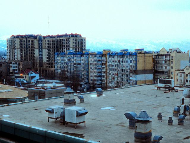 A flat membrane roof with vents and rooftop units on a city building