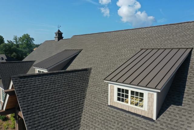 Two dormers finished in dark standing-seam metal on a gray architectural-shingle roof