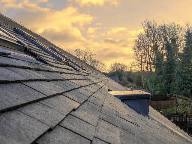Close view along a worn asphalt shingle roof at dusk