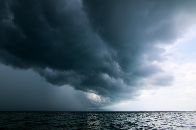 Dark storm clouds rolling in low over open water